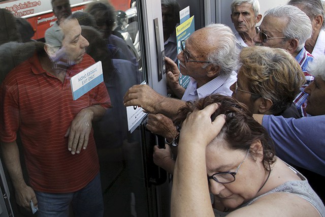 Pensioners waiting outside a closed National Bank branch and hoping to get their pensions, argue with a bank employee (L) in Iraklio on the island of Crete, Greece June 29, 2015. Greeks struggled to adjust to shuttered banks, closed cash machines and a climate of rumours and conspiracy theories on Monday as a breakdown in talks between Athens and its creditors plunged the country deep into crisis.    REUTERS/Stefanos Rapanis   - RTX1I94A