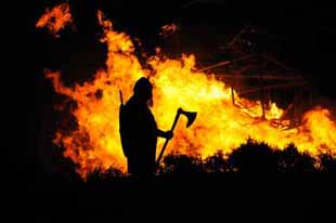 A Viking watches as a building burns.